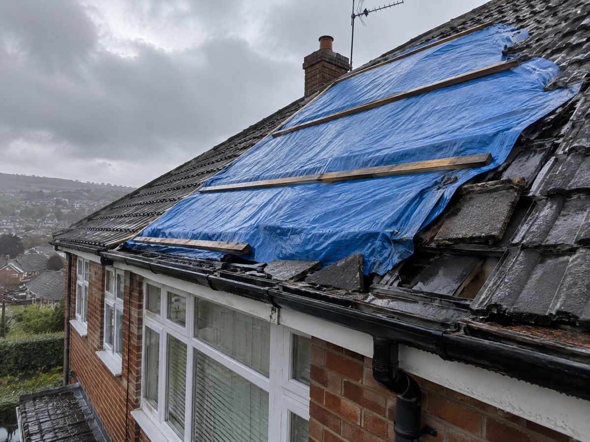 Temporary tarpaulin cover on a storm-damaged UK roof