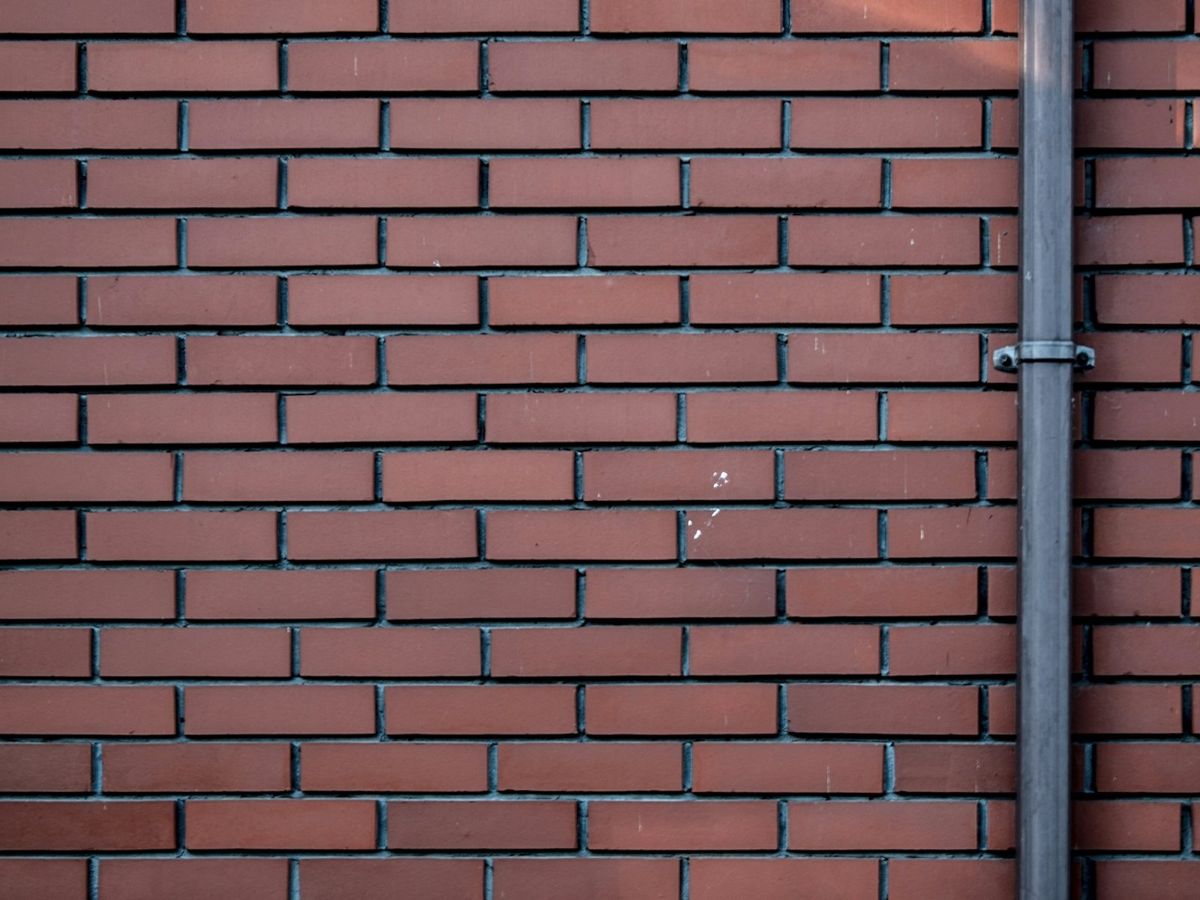 Downpipe running down a red-brick wall