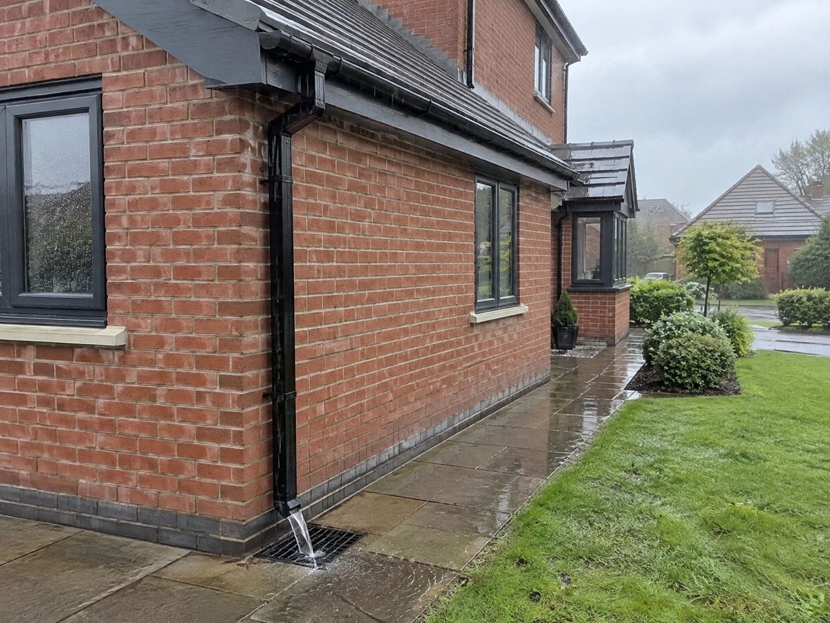 Black UPVC downpipe on a UK brick house